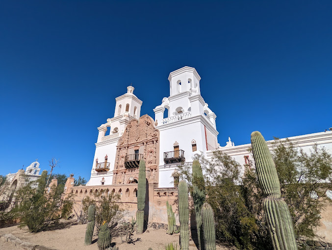 A view of the front entrance of San Xavier del Bac Mission in Tucson - cactus and tumbleweed grow along the front face