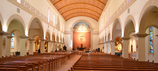 A view of the interior of St. Augustine Cathedral in Tucson - arched architecture and beautiful warmly-lit altar in the distance